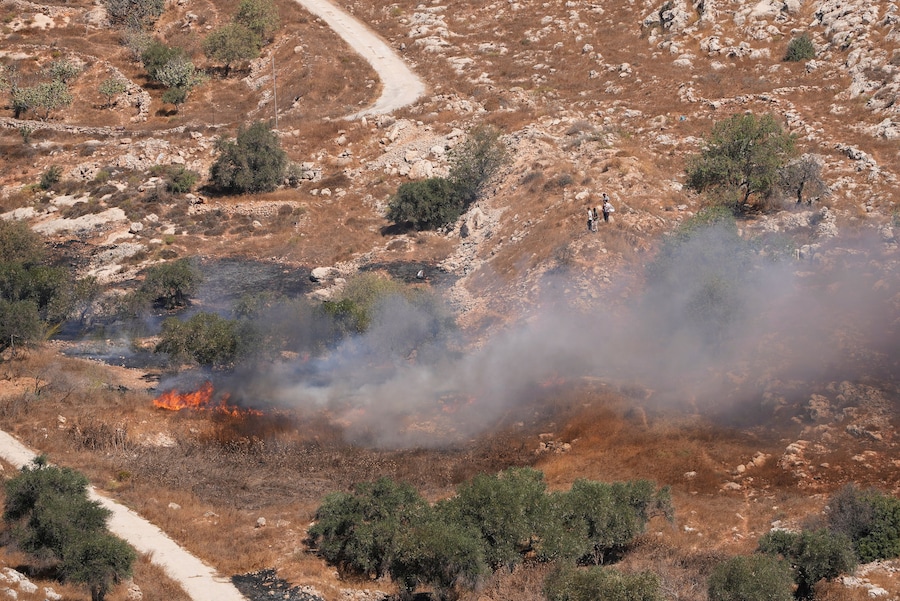 Coloni israeliani in piedi mentre fumo e fiamme si levano dagli uliveti che, secondo i palestinesi, sarebbero stati incendiati dai coloni israeliani, a Burqa, nella Cisgiordania occupata da Israele, il 17 settembre 2026. (REUTERS)