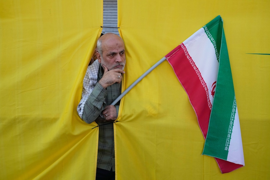 Un uomo con in mano una bandiera iraniana sbircia attraverso un’apertura nella tenda durante la parata in stile militare “Janfada”, ovvero “Sacrificio per l’Iran”, organizzata dallo Stato a Teheran, in Iran. (APN)