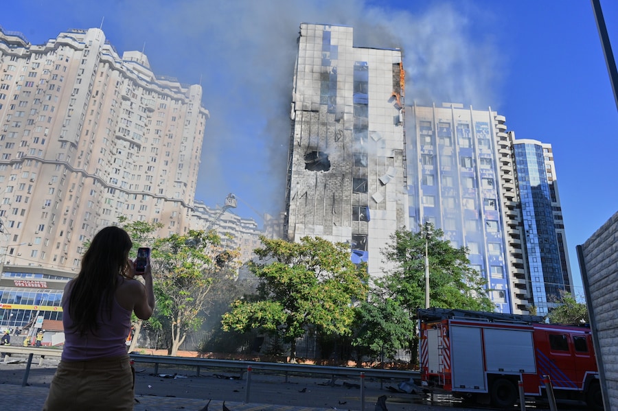 Una donna riprende un edificio adibito a uffici in fiamme a seguito di un attacco con droni russi nel centro di Odessa. (APN)