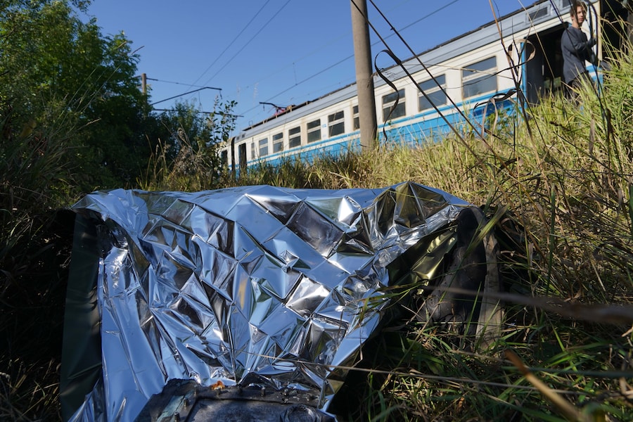 Il corpo di un passeggero giace coperto da una coperta di emergenza vicino a un treno pendolare bruciato, in seguito a un attacco con droni russi contro una stazione ferroviaria nel comune di Novovodolazka, nella regione di Kharkiv. (APN)