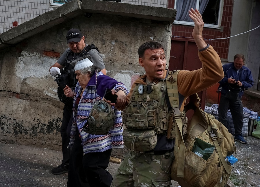 Un agente di polizia e un volontario aiutano un residente a uscire da un edificio, distrutto da un attacco aereo russo, che fungeva da centro di transito per le persone evacuate da una zona di prima linea, nel contesto dell’attacco della Russia all’Ucraina, nella città di Kramatorsk, in Ucraina. (REUTERS)