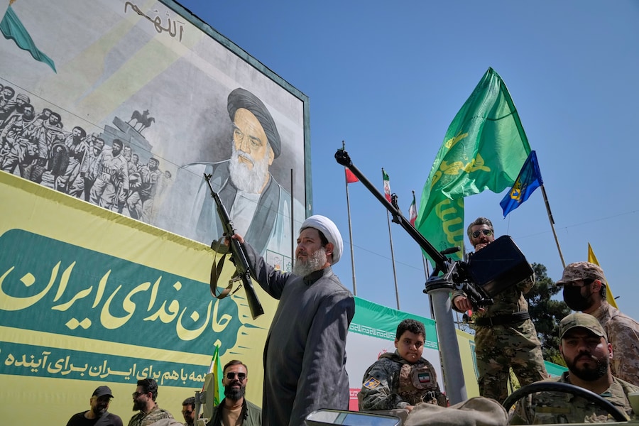 Un religioso sciita armato a bordo di un veicolo militare passa davanti a un cartellone che raffigura l’Ayatollah Ruhollah Khomeini, fondatore della Repubblica Islamica, durante la parata in stile militare “Janfada”, ovvero “Sacrificio per l’Iran”, organizzata dallo Stato a Teheran. (Foto AP/Vahid Salemi/APN)