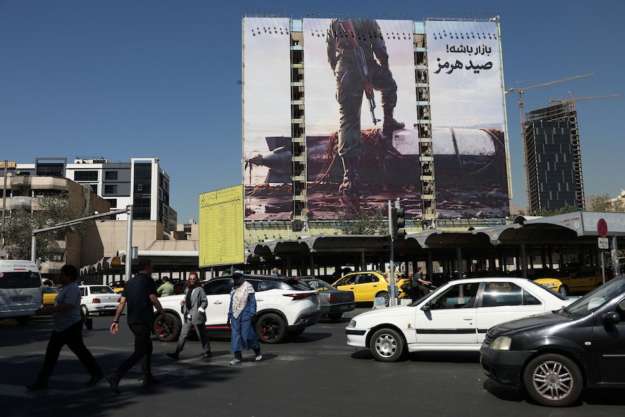 A Teheran, alcune persone passano davanti a un cartellone pubblicitario con l’immagine di un sommergibile senza equipaggio statunitense. (Majid Asgaripour/WANA (West Asia News Agency) via REUTERS)