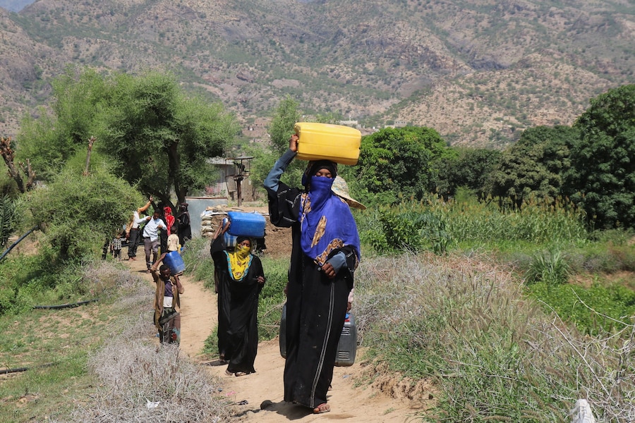 Alcune persone trasportano taniche mentre raccolgono acqua per un accampamento di fortuna destinato agli sfollati a causa degli scontri tra i combattenti Houthi, alleati dell’Iran, e le forze governative yemenite sostenute dall’Arabia Saudita, nella provincia di Taiz, nello Yemen. (REUTERS/Ebrahim Al-Suhaibi)