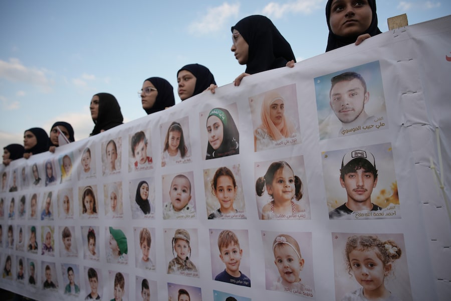 Durante una manifestazione a Beirut, in Libano, alcune ragazze reggono uno striscione su cui sono raffigurati i ritratti e i nomi di alcuni degli oltre 750 bambini libanesi uccisi dal 2024 nella guerra tra Israele e Hezbollah, mercoledì 23 settembre 2026. (AP Photo/Hassan Ammar/APN)