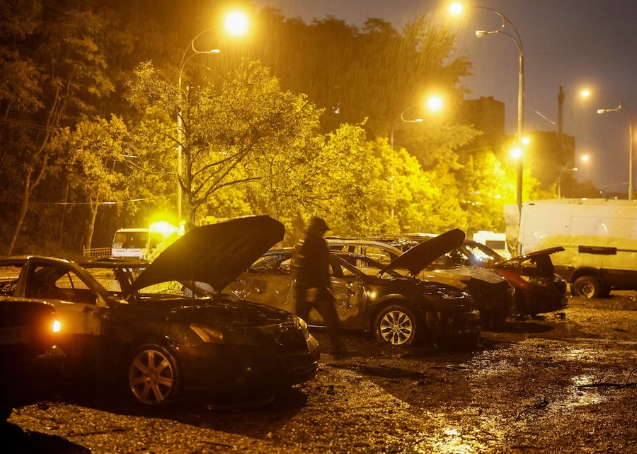 Un abitante cammina vicino ad alcune auto distrutte sul luogo di un attacco missilistico russo nei pressi di un ospedale maternità, nel contesto dell'offensiva russa contro l'Ucraina a Kiev. (REUTERS)