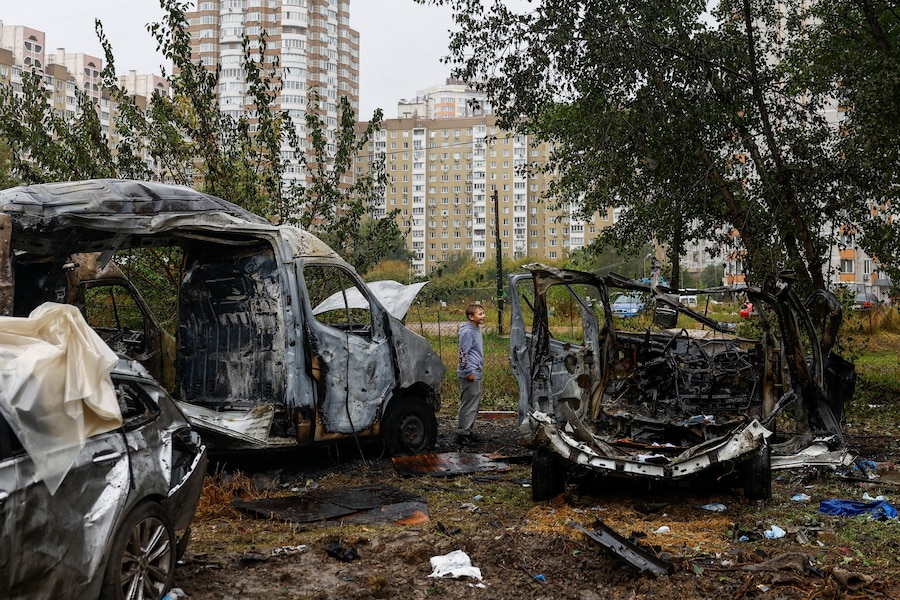 Un ragazzo si trova accanto ad alcuni veicoli colpiti da un attacco con droni russi in un parcheggio di una zona residenziale, nel contesto dell'attacco della Russia all'Ucraina, a Kiev. (REUTERS)