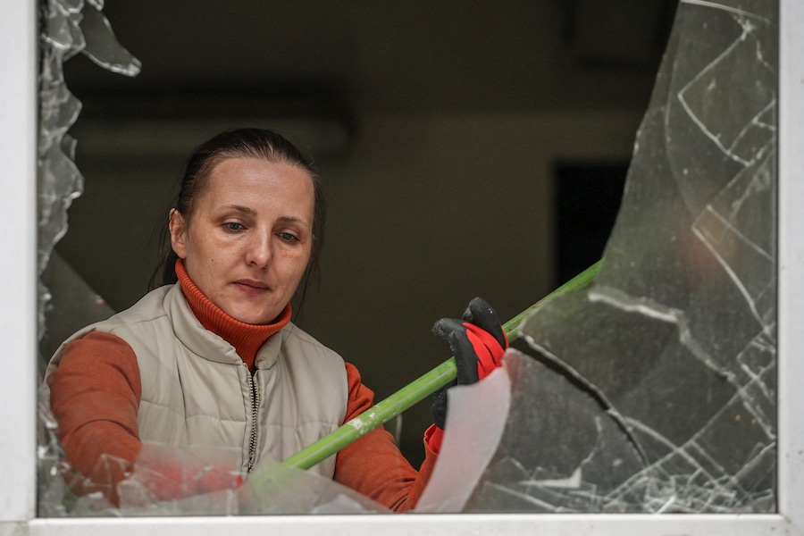 Un dipendente di un centro di assistenza sanitaria di base raccoglie i frammenti di vetro delle finestre in frantumi sul luogo di un attacco missilistico russo, nel contesto dell'offensiva russa contro l'Ucraina, a Kiev. (REUTERS)