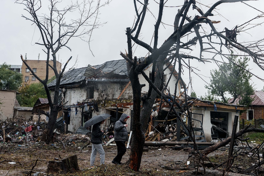 Alcune persone passano davanti a una casa gravemente danneggiata da un attacco russo contro un quartiere residenziale di Kiev. (APN)
