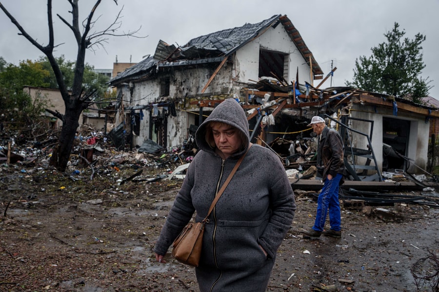 Una donna cammina davanti a una casa gravemente danneggiata da un attacco russo contro un quartiere residenziale di Kiev. (APN)