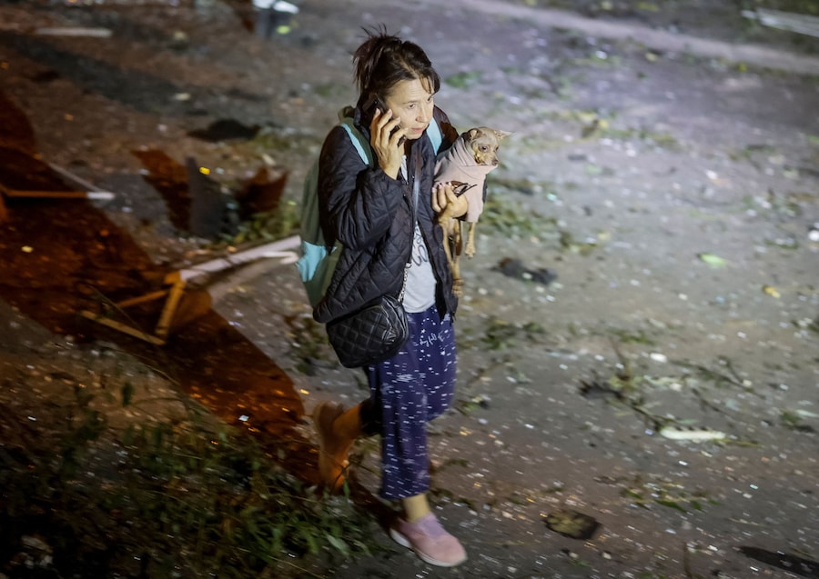 Una donna con il suo cane abbandona un condominio danneggiato da un attacco di droni a Kiev. (REUTERS)