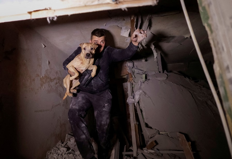 Un residente con il suo cane esce da un condominio danneggiato da un attacco aereo russo a Kharkiv, Ucraina, il 28 settembre 2026. (REUTERS)