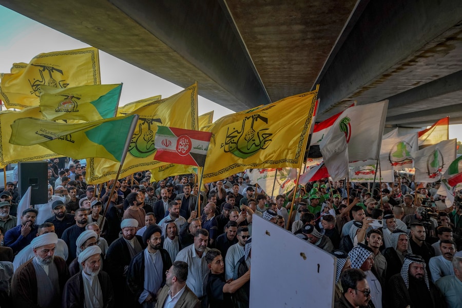I manifestanti sventolano bandiere, tra cui quelle della milizia irachena Harakat Hezbollah al-Nujaba, vicina all’Iran, durante una protesta contro la sospensione dei voli tra Iraq e Iran davanti all’aeroporto internazionale di Najaf, a Najaf, in Iraq. (APN)