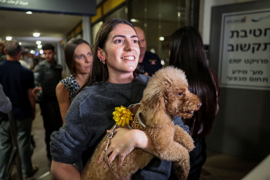 Una donna tiene in braccio un cane mentre i passeggeri dell’aereo della FlyDubai diretto in Israele dagli Emirati Arabi Uniti, deviato in Arabia Saudita a seguito di un segnale di emergenza, arrivano all’aeroporto internazionale Ben Gurion, a Lod, vicino a Tel Aviv. (REUTERS)