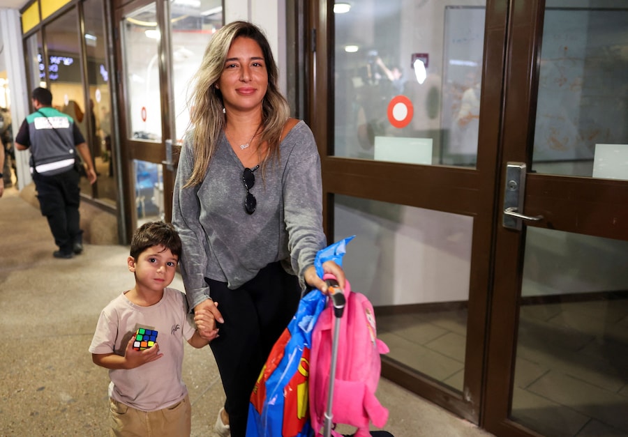Una donna cammina con un bambino, mentre i passeggeri che si trovavano a bordo dell’aereo della FlyDubai diretto in Israele dagli Emirati Arabi Uniti – dirottato in Arabia Saudita a seguito di un segnale di emergenza – arrivano all’aeroporto internazionale Ben Gurion, a Lod, vicino a Tel Aviv. (REUTERS)