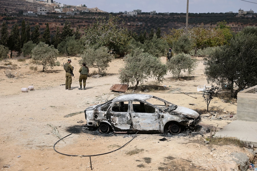 Membri delle forze di sicurezza israeliane in piedi accanto a un veicolo distrutto nella proprietà dei palestinesi Mahmod Tubasi, 60 anni, e di sua moglie Aedah, 51 anni, che sostengono sia stata attaccata da coloni israeliani, a Jalud, nella Cisgiordania occupata da Israele, il 29 settembre 2026. REUTERS/Ammar Awad (REUTERS)
