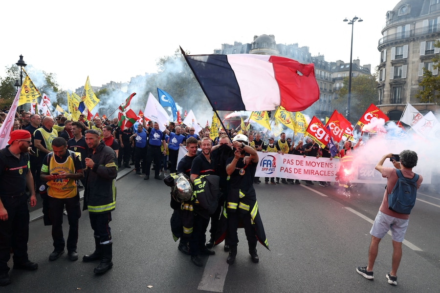 I vigili del fuoco francesi sventolano una bandiera francese durante una manifestazione per chiedere maggiori risorse e finanziamenti dopo un’estate segnata da incendi di vaste proporzioni, a Parigi, nell’ambito di una giornata di scioperi e proteste dei lavoratori del settore pubblico in Francia, il 29 settembre 2026. REUTERS/Tom Nicholson (REUTERS)
