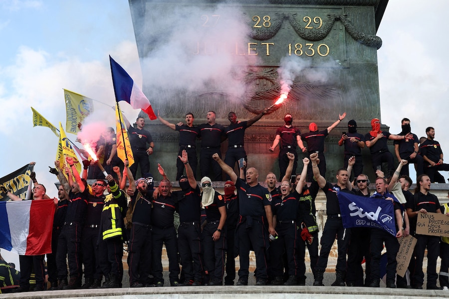 I vigili del fuoco francesi, con in mano bandiere francesi e razzi di segnalazione rossi, si radunano in Place de la Bastille durante una manifestazione per chiedere maggiori risorse e finanziamenti dopo un’estate segnata da incendi di vaste proporzioni, a Parigi, nell’ambito di una giornata di scioperi e proteste dei lavoratori del settore pubblico in Francia, il 29 settembre 2026. REUTERS/Abdul Saboor (REUTERS)