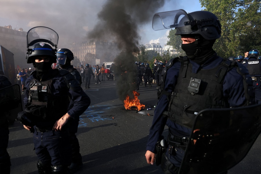 Agenti di polizia francesi accanto a uno pneumatico in fiamme durante una manifestazione dei vigili del fuoco francesi in sciopero, che chiedono maggiori risorse e finanziamenti dopo un'estate segnata da incendi di vaste proporzioni, a Parigi, nell'ambito di una giornata di scioperi e proteste dei lavoratori del settore pubblico in Francia, il 29 settembre 2026. REUTERS/Tom Nicholson (REUTERS)