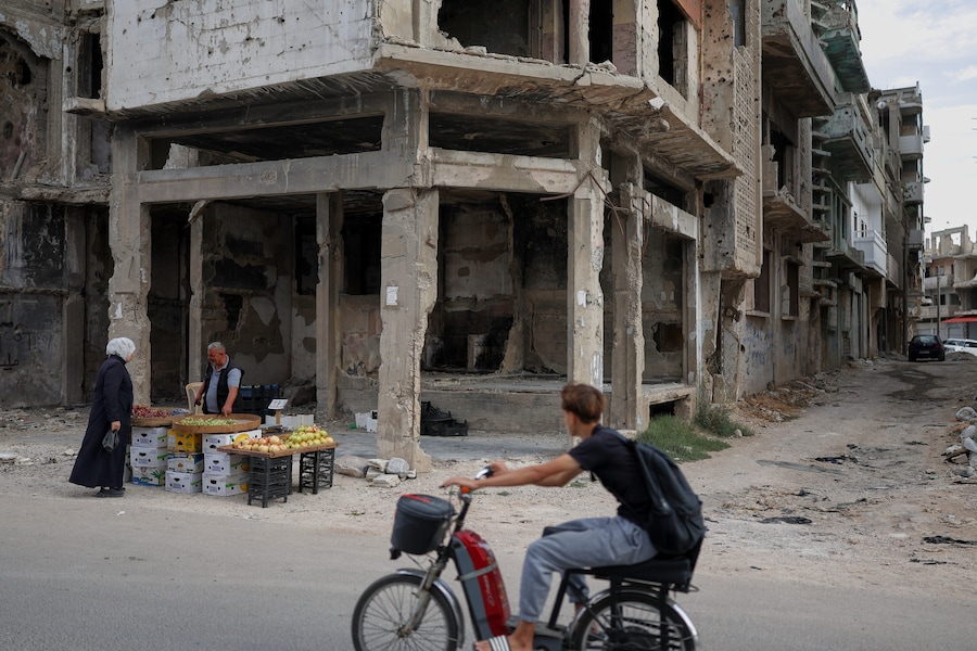 Un venditore di frutta parla con una donna presso la sua bancarella lungo la strada, davanti a un edificio danneggiato durante la guerra civile a Homs, in Siria, giovedì 1 ottobre 2026. (Foto AP/Ghaith Alsayed) (APN)