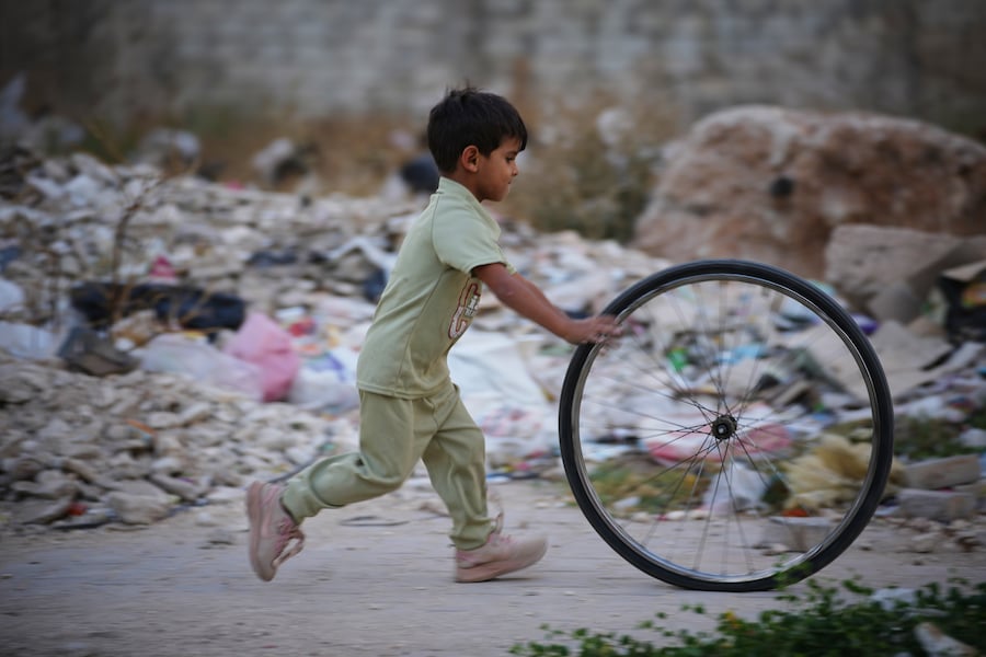 Un ragazzino spinge una ruota di bicicletta tra le macerie mentre gioca in un quartiere danneggiato durante la guerra civile a Homs, in Siria, giovedì 1 ottobre 2026. (Foto AP/Ghaith Alsayed) (APN)