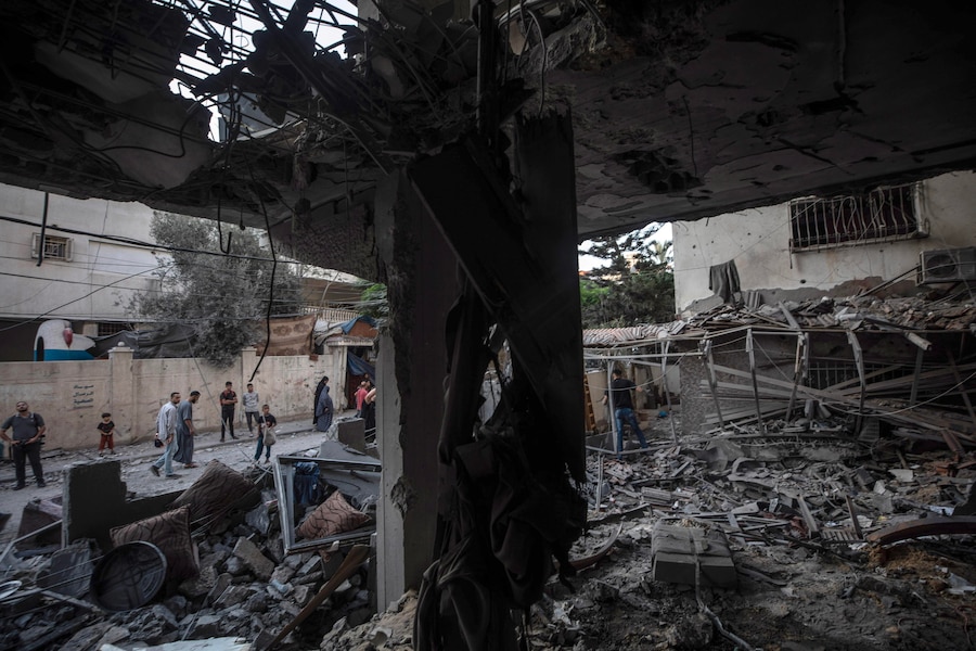 Alcuni palestinesi ispezionano le macerie di un condominio residenziale in seguito a un attacco aereo israeliano nella zona occidentale della città di Gaza (EPA)