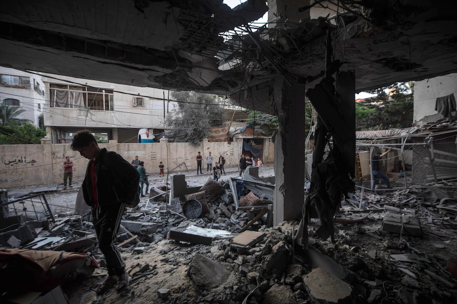 Alcuni palestinesi ispezionano le macerie di un condominio residenziale in seguito a un attacco aereo israeliano nella zona occidentale della città di Gaza (EPA)