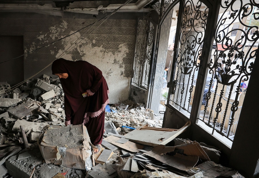 Una donna palestinese ispeziona il luogo in cui si è verificato un attacco israeliano contro un condominio nella città di Gaza (REUTERS)