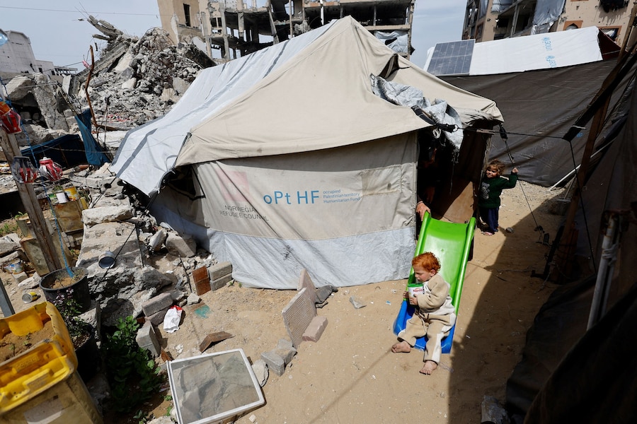 Ibrahim Badr, 3 anni, evacuato da Gaza quando era un neonato prematuro per ricevere cure in Egitto, gioca davanti a una tenda presso l’Università Islamica di Gaza City (REUTERS)