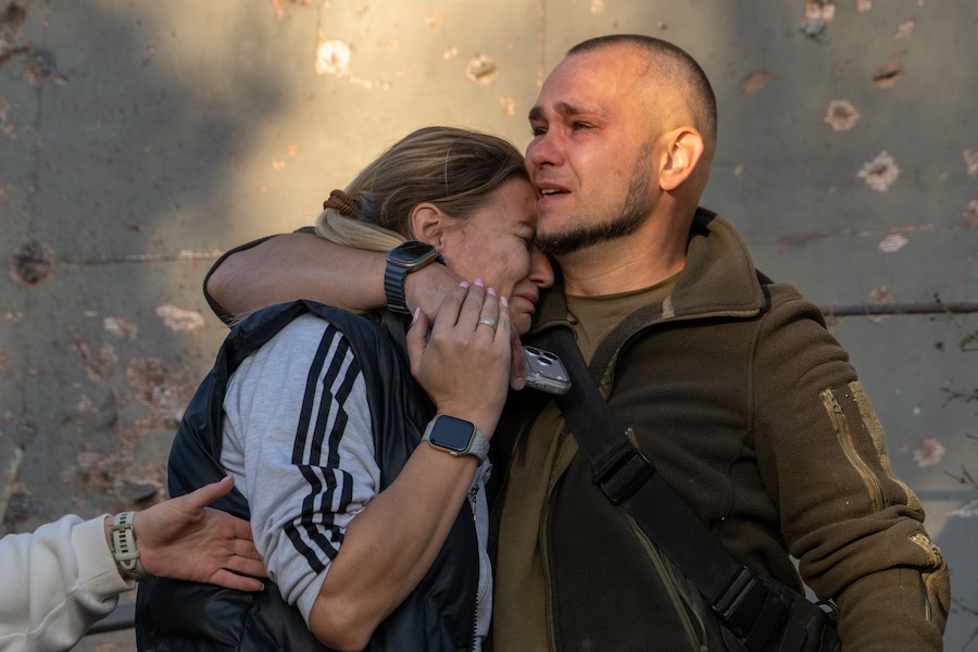 Un uomo abbraccia una donna dopo aver riconosciuto il corpo di sua nonna, rimasta uccisa in un attacco aereo russo su un quartiere residenziale di Kharkiv, in Ucraina (APN)