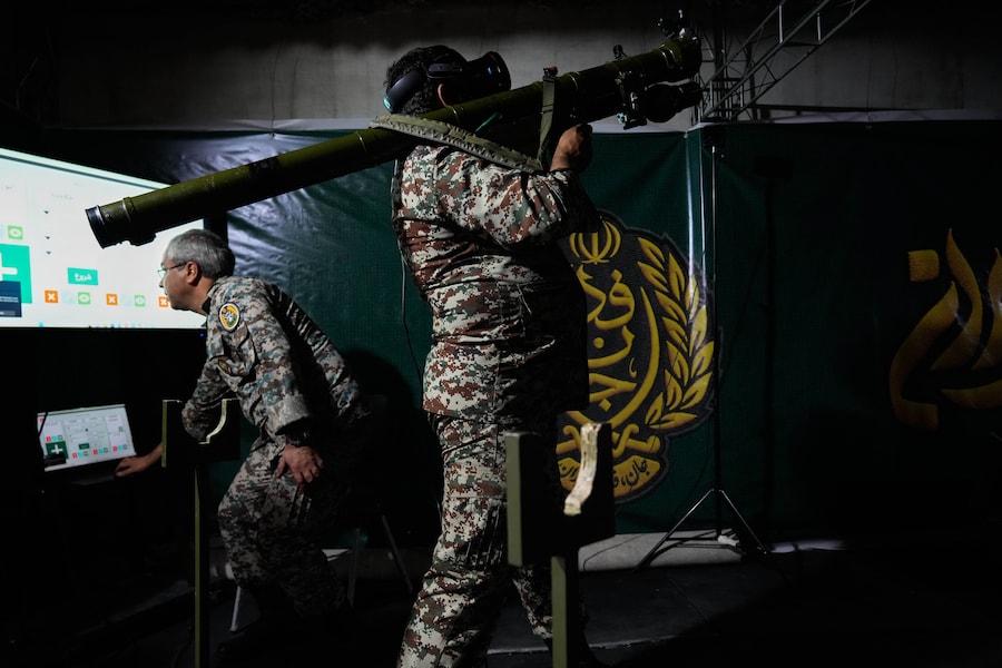 Un membro dell'esercito iraniano mostra il funzionamento di un'arma portatile con l'ausilio di un simulatore durante la cerimonia di inaugurazione di uno dei centri di addestramento militare per volontari che stanno sorgendo nelle piazze del centro di Teheran, in Iran (APN)