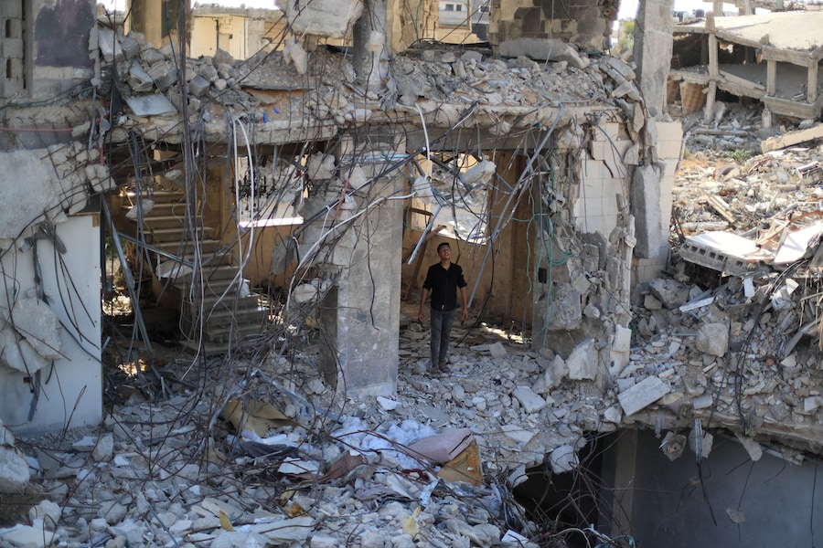 Un giovane palestinese in piedi tra le macerie di edifici residenziali distrutti durante la guerra, nella città di Gaza (REUTERS)