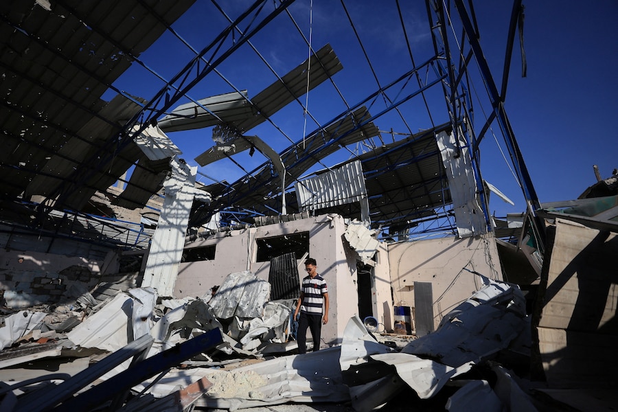 Un giovane palestinese in piedi tra le macerie del magazzino dell’azienda della famiglia Al-Hassayna, danneggiato durante la guerra, nella città di Gaza (REUTERS)