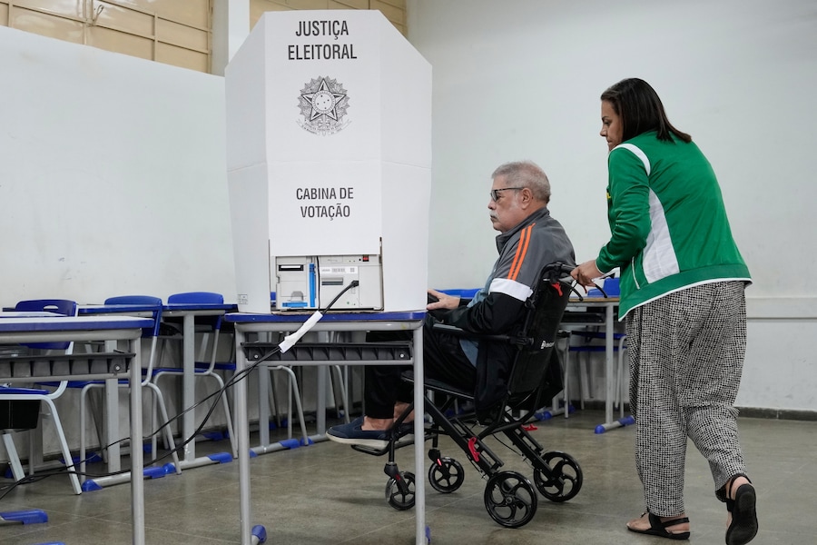 Una donna accompagna un elettore verso una macchina per il voto elettronico durante le elezioni generali a Brasilia, in Brasile. (APN)