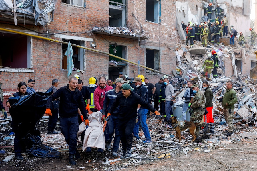 Alcune persone trasportano un ferito, mentre i soccorritori lavorano per trarre in salvo i residenti sepolti sotto le macerie sul luogo di un condominio colpito da un missile russo nella città di Pryluky, nel contesto dell’attacco della Russia all’Ucraina, nella regione di Chernihiv. (REUTERS)