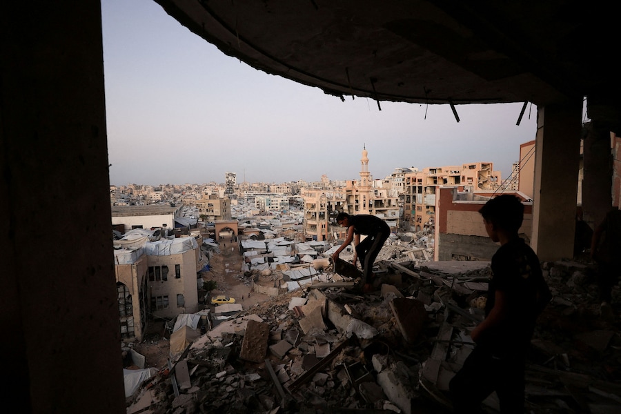 Un uomo palestinese lavora tra le macerie di un edificio danneggiato durante la guerra, con alle spalle un accampamento di tende improvvisato presso l'Università Islamica, nella città di Gaza. REUTERS/Dawoud Abu Alkas (REUTERS)