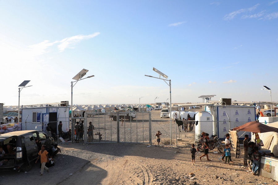 Alcune persone camminano nei pressi del cancello di un accampamento di fortuna per sfollati a causa degli scontri tra i combattenti Houthi, alleati dell’Iran, e le forze governative yemenite sostenute dall’Arabia Saudita, nei pressi di Aden, nello Yemen, l’8 ottobre 2026. REUTERS/Stringer (REUTERS)