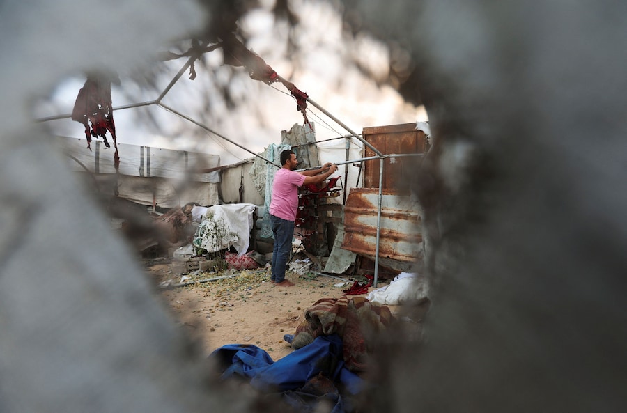 Un uomo palestinese ispeziona il luogo in cui un attacco israeliano ha colpito una tenda a Khan Younis, nella parte meridionale della Striscia di Gaza (REUTERS)