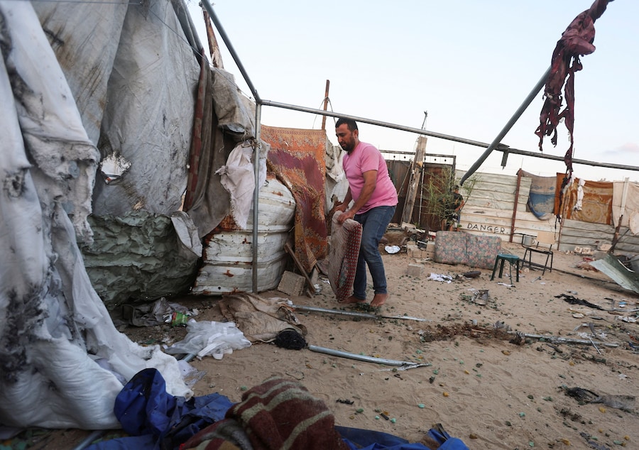 Un uomo palestinese ispeziona il luogo in cui un attacco israeliano ha colpito una tenda a Khan Younis, nella parte meridionale della Striscia di Gaza, (REUTERS)