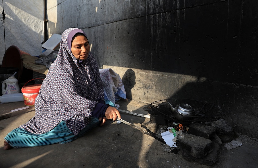 Una donna palestinese sfollata prepara il tè fuori dalla sua tenda in un campo profughi, nella città di Gaza (REUTERS)