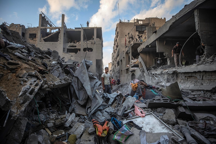 Alcuni palestinesi ispezionano le macerie delle case distrutte in seguito a un attacco aereo israeliano nel quartiere di Al-Sabra a Gaza City (EPA)
