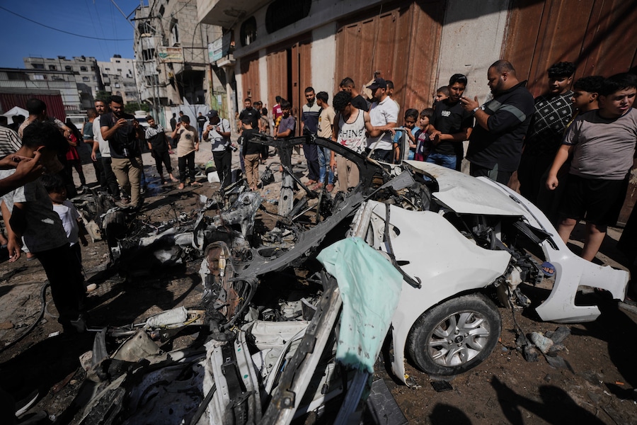 I palestinesi ispezionano i rottami di un’auto colpita da un attacco israeliano nella città di Gaza (APN)