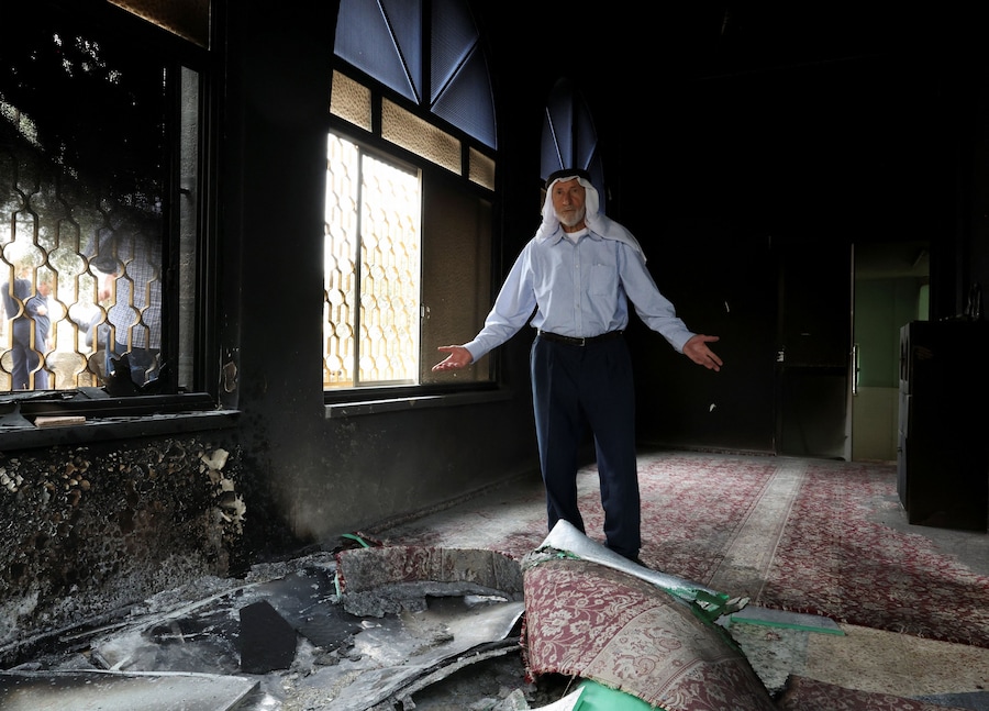 Un palestinese ispeziona i danni subiti da una moschea, che secondo i palestinesi sarebbe stata incendiata dai coloni israeliani, a Mukhmas, nei pressi di Ramallah, nella Cisgiordania occupata da Israele (REUTERS)