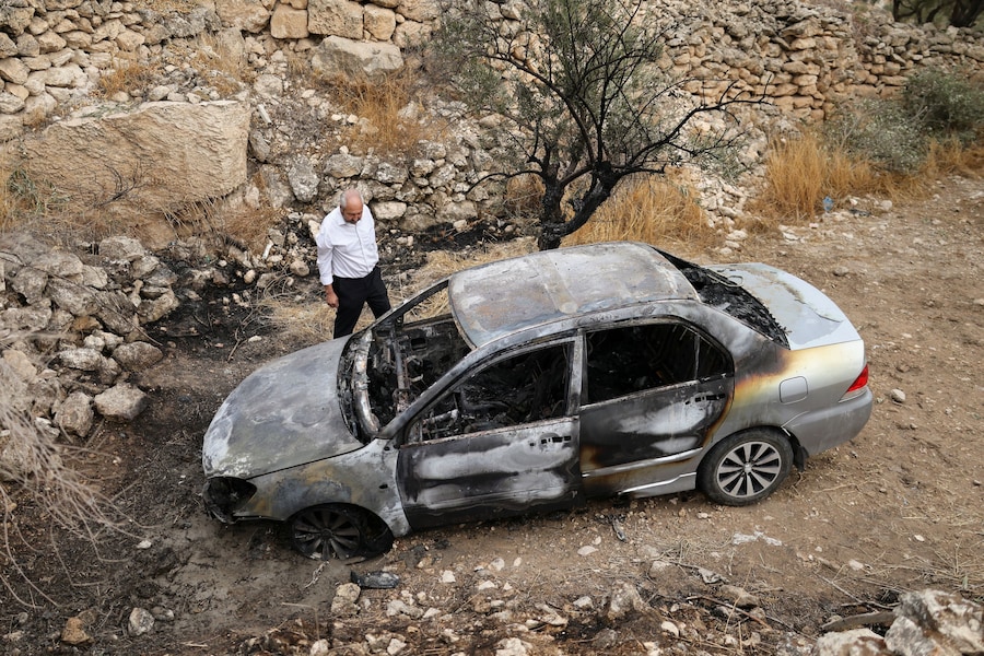 Un palestinese ispeziona un'auto danneggiata, che secondo i palestinesi sarebbe stata incendiata dai coloni israeliani, a Mukhmas, nei pressi di Ramallah, nella Cisgiordania occupata da Israele (REUTERS)