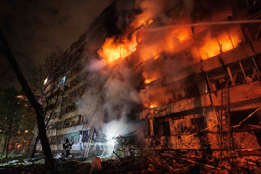 Un soccorritore spegne un incendio divampato in un edificio residenziale a più piani danneggiato da un attacco missilistico russo a Kiev (APN)
