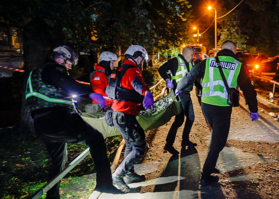 Medici e agenti di polizia ucraini trasportano il corpo di una vittima sul luogo di un attacco missilistico russo contro un edificio residenziale a Kiev (EPA)