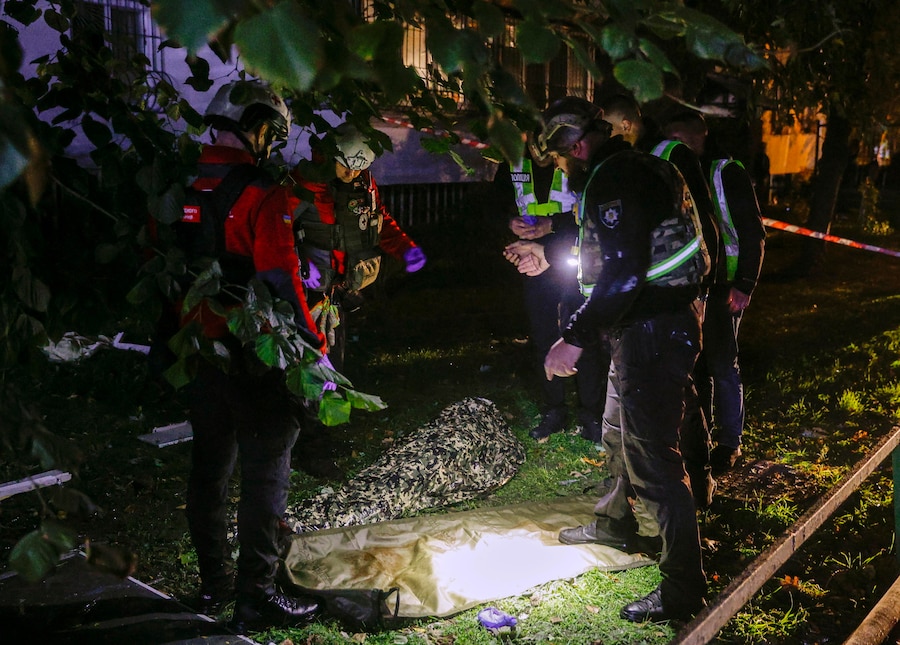 Medici e agenti di polizia ucraini si occupano del corpo di una vittima sul luogo di un attacco missilistico russo contro un edificio residenziale a Kiev (EPA)