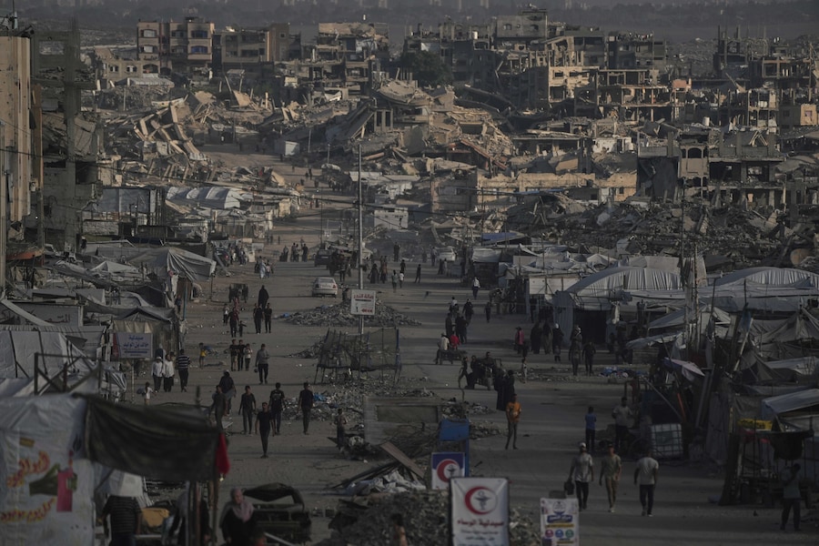 Alcuni palestinesi camminano lungo una strada fiancheggiata da edifici distrutti durante la guerra tra Israele e Hamas nella città di Gaza. (Foto AP/Jehad Alshrafi) (APN)
