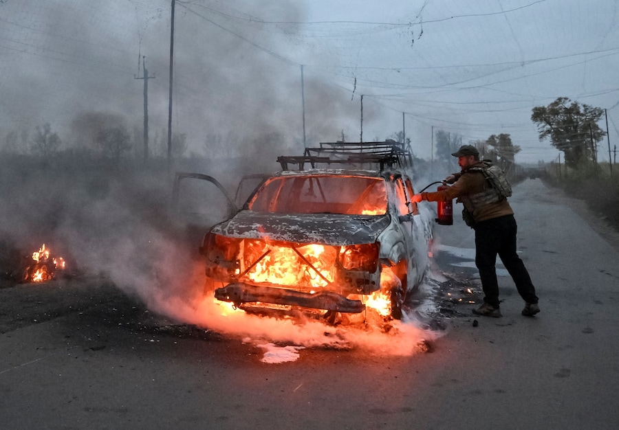 Un militare spegne un’auto in fiamme colpita da un drone FPV russo nella regione di Donetsk, Ucraina (REUTERS)