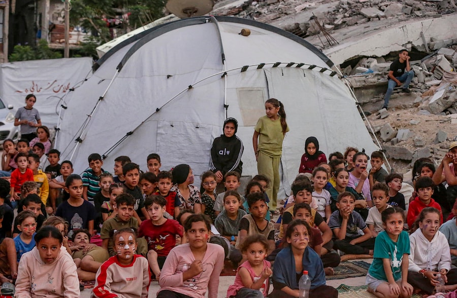 Bambini palestinesi sfollati all’interno del proprio Paese guardano un film in un cinema all’aperto improvvisato vicino alle rovine di edifici distrutti nel quartiere di Al-Sheikh Redwan a Gaza City, il 15 ottobre 2026. Secondo le Nazioni Unite, circa 1,9 milioni di persone a Gaza, quasi il 90% della popolazione, sono state sfollate dall’inizio del conflitto tra Israele e Hamas nell’ottobre 2023. EPA/MOHAMMED SABER (EPA)